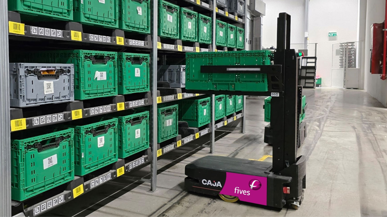 Caja by Fives uses a dual-robot approach to separate high-density vertical storage from horizontal transport, orchestrated by AI-driven software.